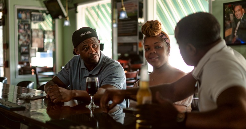 Three people seated at the bar counter with drinks
