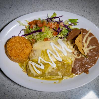 Green enchiladas served with rice, refried beans, and a side salad with pico de gallo.