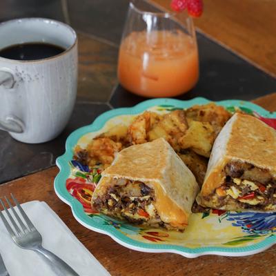 Smoked Brisket Burrito with seasoned potatoes, a coffee, and a grapefruit mimosa.