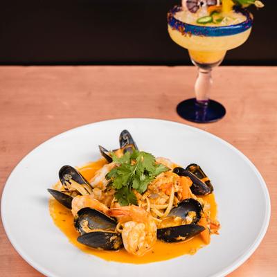 Mussels, shrimp and pasta dish served, accompanied by a cocktail