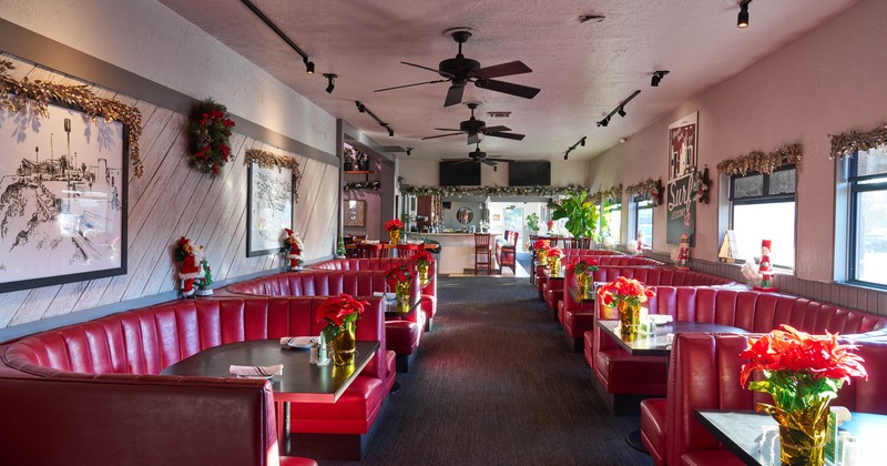 Interior of a restaurant with red leather booths, black tables, and holiday decorations