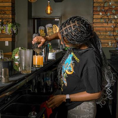 A bartender pouring a mixed drink.