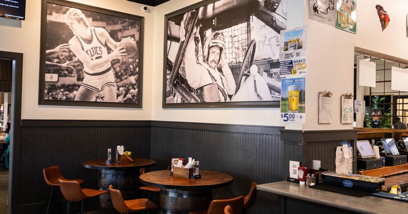 Restaurant interior with large black-and-white photos and wooden barrel tables