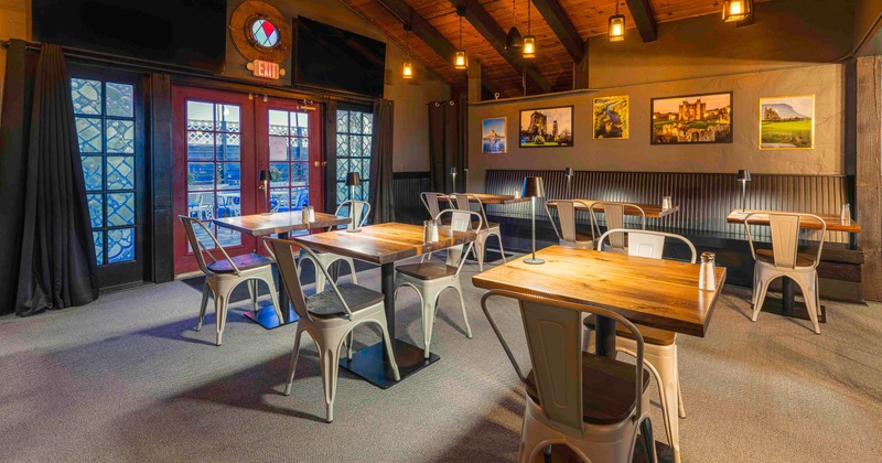 A cozy dining space with wooden tables, metal chairs and photographs on the walls