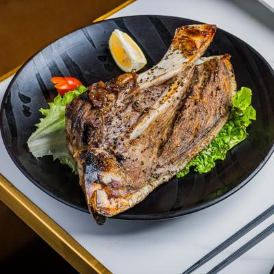 Fresh Blue Fin Kama served on a bed of lettuce with a lemon wedge.