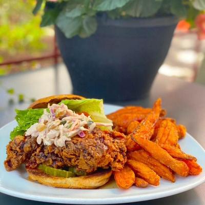 Fried chicken sandwich with coleslaw and sweet potato fries.