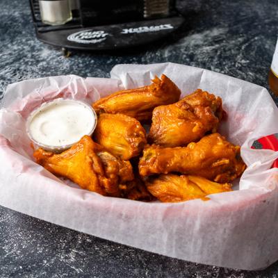 A basket of buffalo wings served with dipping sauce.