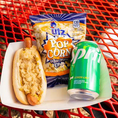 Hot dog with sauerkraut, served with a soda can and a bag of pop corn.