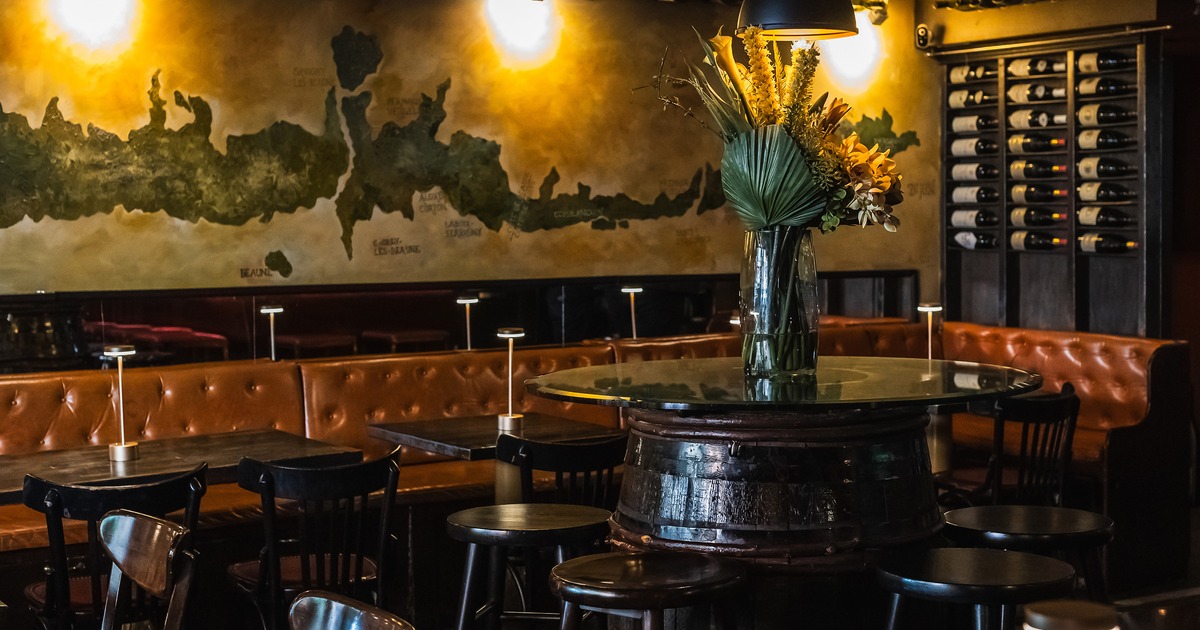 A cozy and upscale lounge seating area with dark wooden tables and tufted leather booth seating