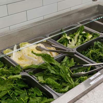 Hot pot ingredient bar featuring various fresh greens and vegetables.