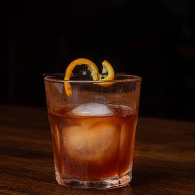 Old Fashioned cocktail with ice sphere and orange peel garnish.