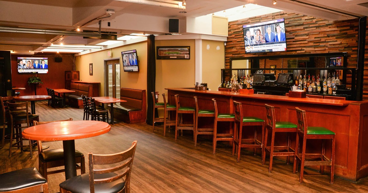 Seating area, the bar with barstools on the right, and three TV screens on the walls