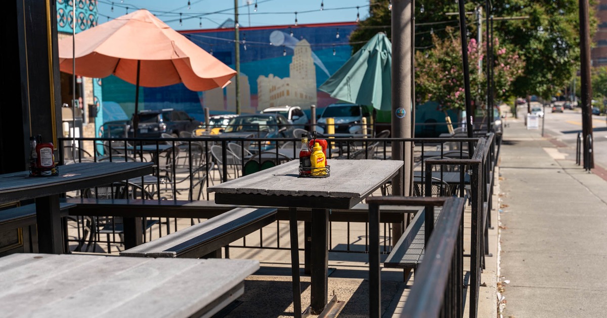 Exterior, front porch, covered seating area, wooden benches and tables, railing