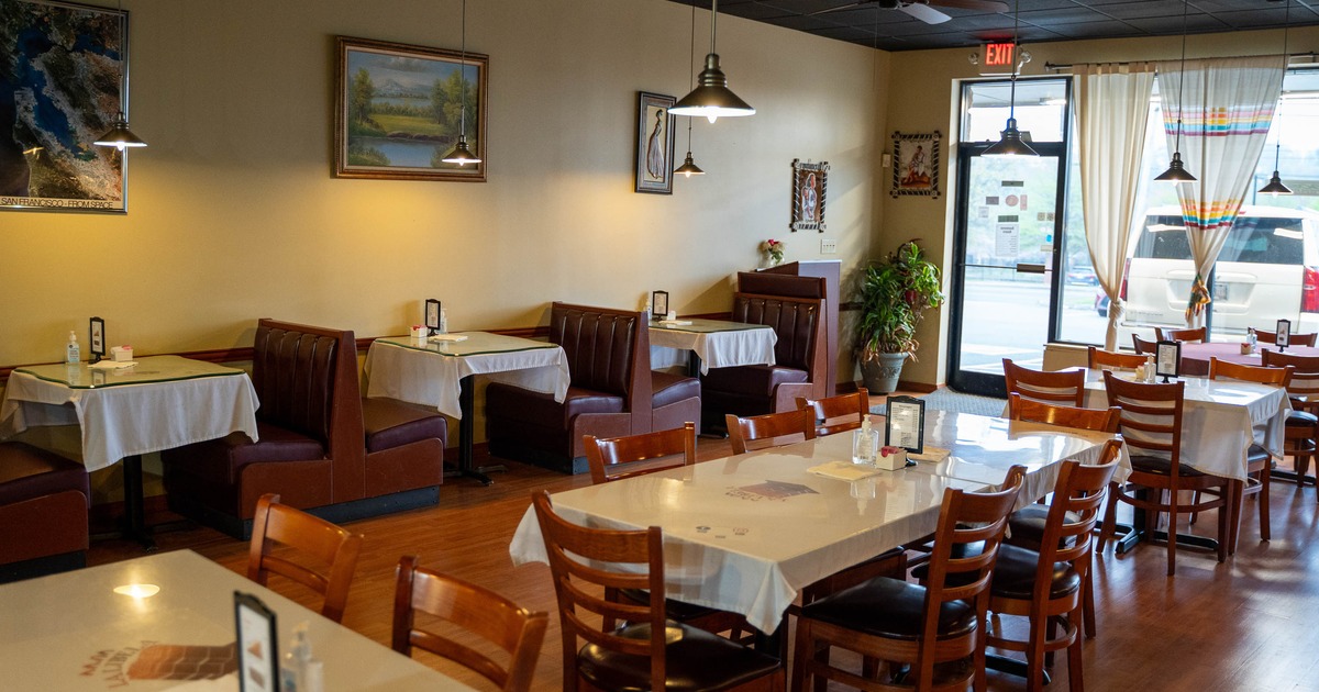 Cozy restaurant interior with wooden tables and chairs, and maroon booth seating along the wall