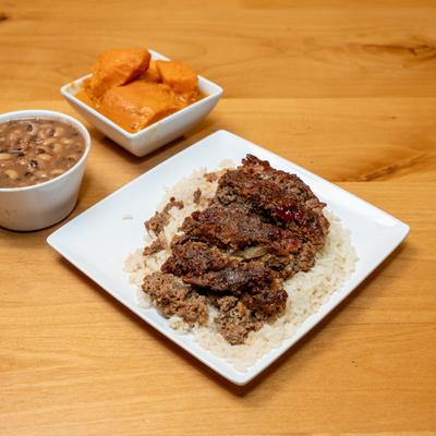 A plate of meatloaf served with a bowl of black eyed peas and a bowl of yams.