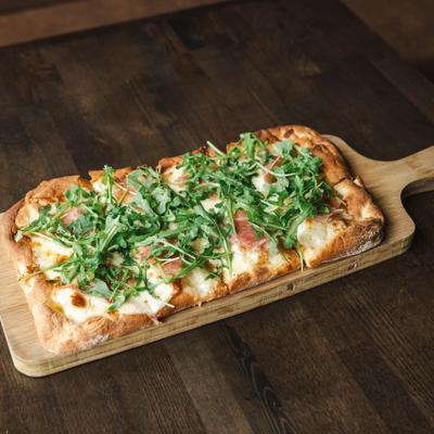 Flatbread with parmesan cream sauce, prpvolone, arugula, prosciutto, and truffle honey.