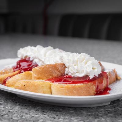 French toast topped with strawberry sauce and whipped cream.
