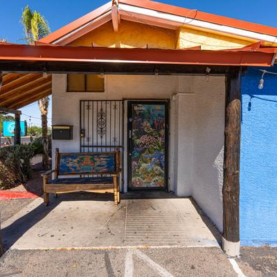 Colorful restaurant entrance with a hand-painted bench and a mural door.