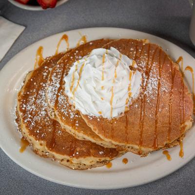 Pancakes topped with whipped cream and syrup.
