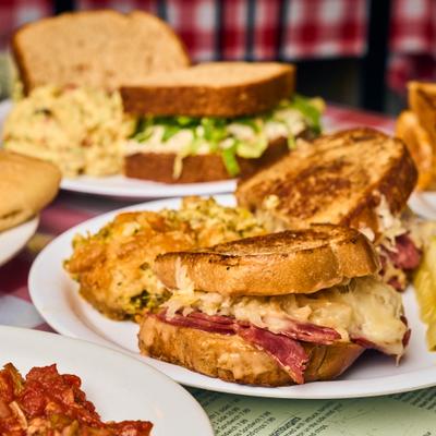 Reuben sandwich served on the table alongside other dishes.