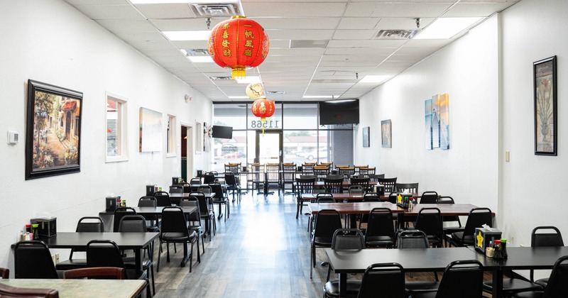 Dining room featuring white walls adorned with framed artwork and red paper lanterns