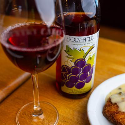 Filled glass and a bottle of red wine on a table, close up.