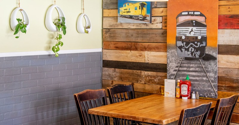 Interior, a dining table in the corner of the room, walls decorated with ceramic hanging plant pot and artwork