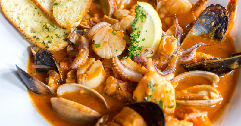 Seafood in sauce, served with garlic bread, closeup