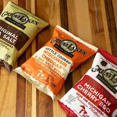 Bags of kettle chips laid on a wooden table.