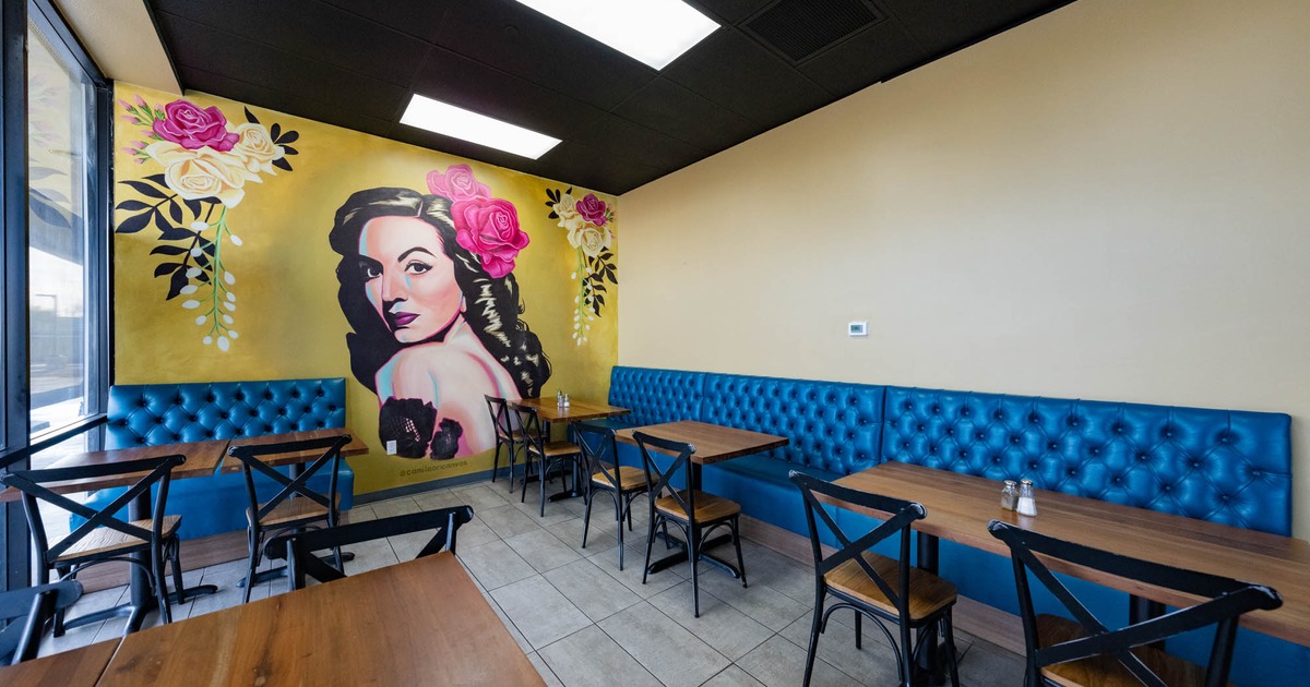 Interior, mural of a woman and flowers on the left wall, blue leather banquette benches