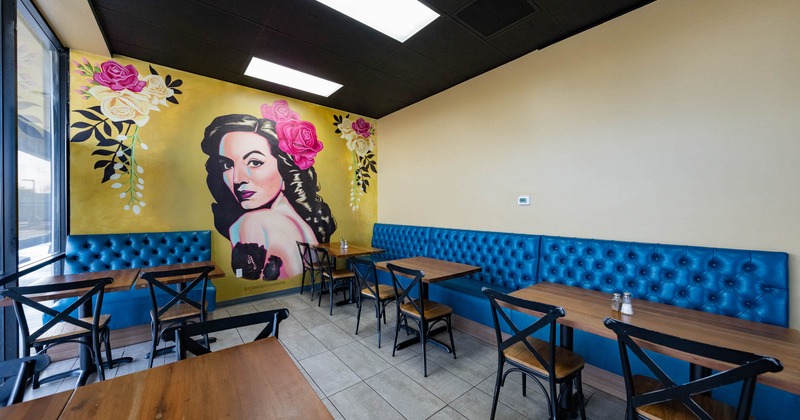 Interior, mural of a woman and flowers on the left wall, blue leather banquette benches