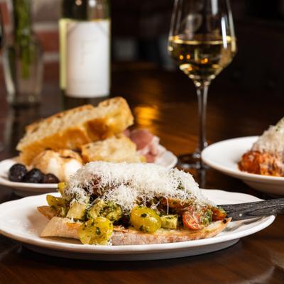 Tomato bruschetta toped with grated cheese with glass of white vine.
