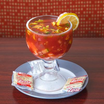 Shrimp cocktail served in a large glass goblet with saltine crackers on the side.