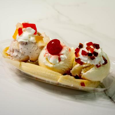 Banana split dessert topped with ice cream scoops and a maraschino cherry.