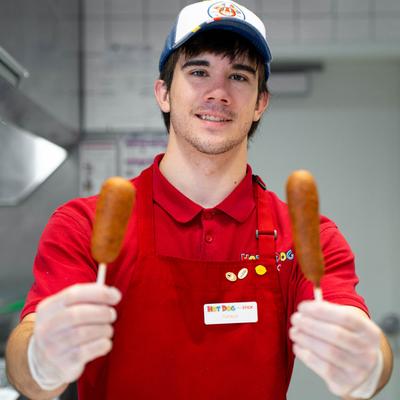 A staff member holding corndogs.