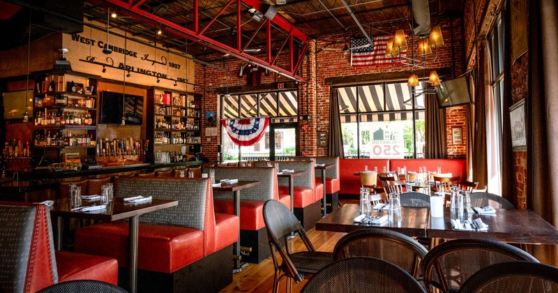 Interior, an industrial design, featuring a bar, red booths, and wooden tables, warm ambiance