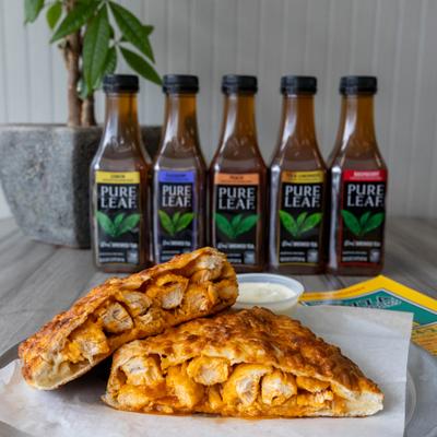 Chicken calzone slices with cheese and iced tea bottles in the background.