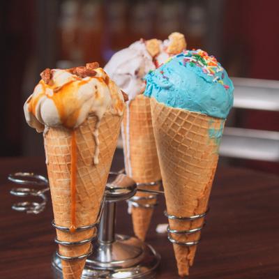 Three loaded ice cream cones served in specialized metal holders.