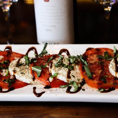 Caprese salad, with mozzarella, tomatoes, garlic, basil, olive oil, and balsamic glaze.