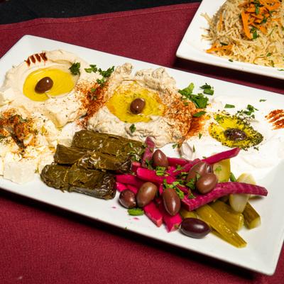 Combo platter with grape leaves, hummus, baba ghanoush, kabis, feta, labneh, and olive oil.