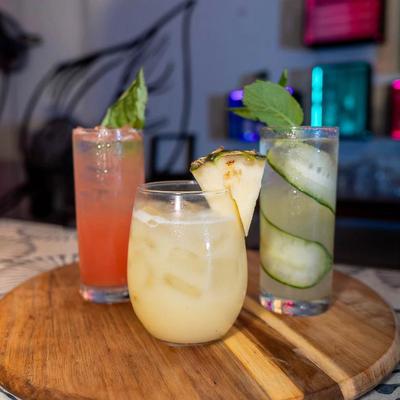 Three different cocktails served on a wooden tray.