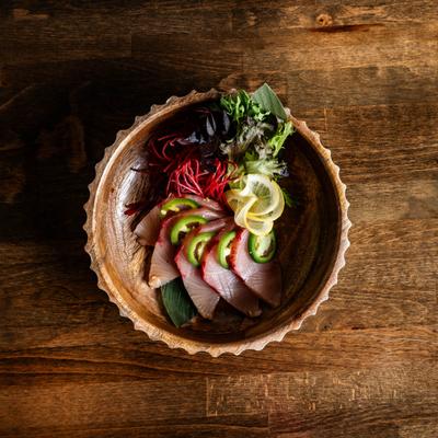 Yellowtail tuna sashimi garnished with jalapeno, lemon, and greens.