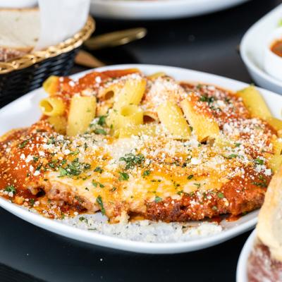 Chicken Parmesan served alongside penne tossed in a tomato-based sauce.