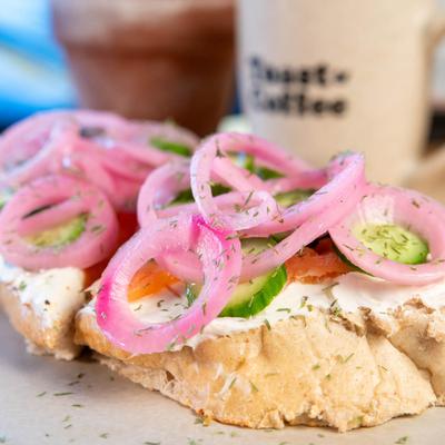 Lox toast with salmon, cucumbers, cream cheese, and onions.