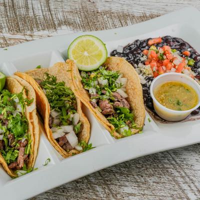 Tacos Del Barrio, served with dip and beans.