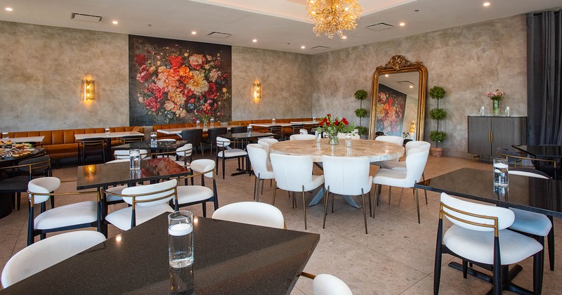 Modern restaurant interior with a large round marble table, floral mural