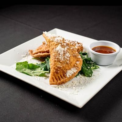 Chicken empanadas served with chili sauce.
