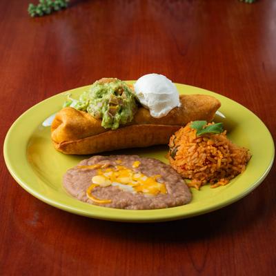 Chimichanga, topped with guacamole and sour cream, and served with rice, and beans.