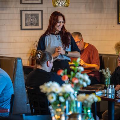 A server greeting guests at a table in a casual restaurant.