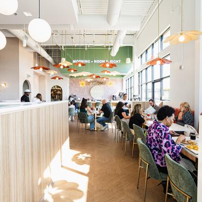 Bright, modern cafe interior with people dining at tables.